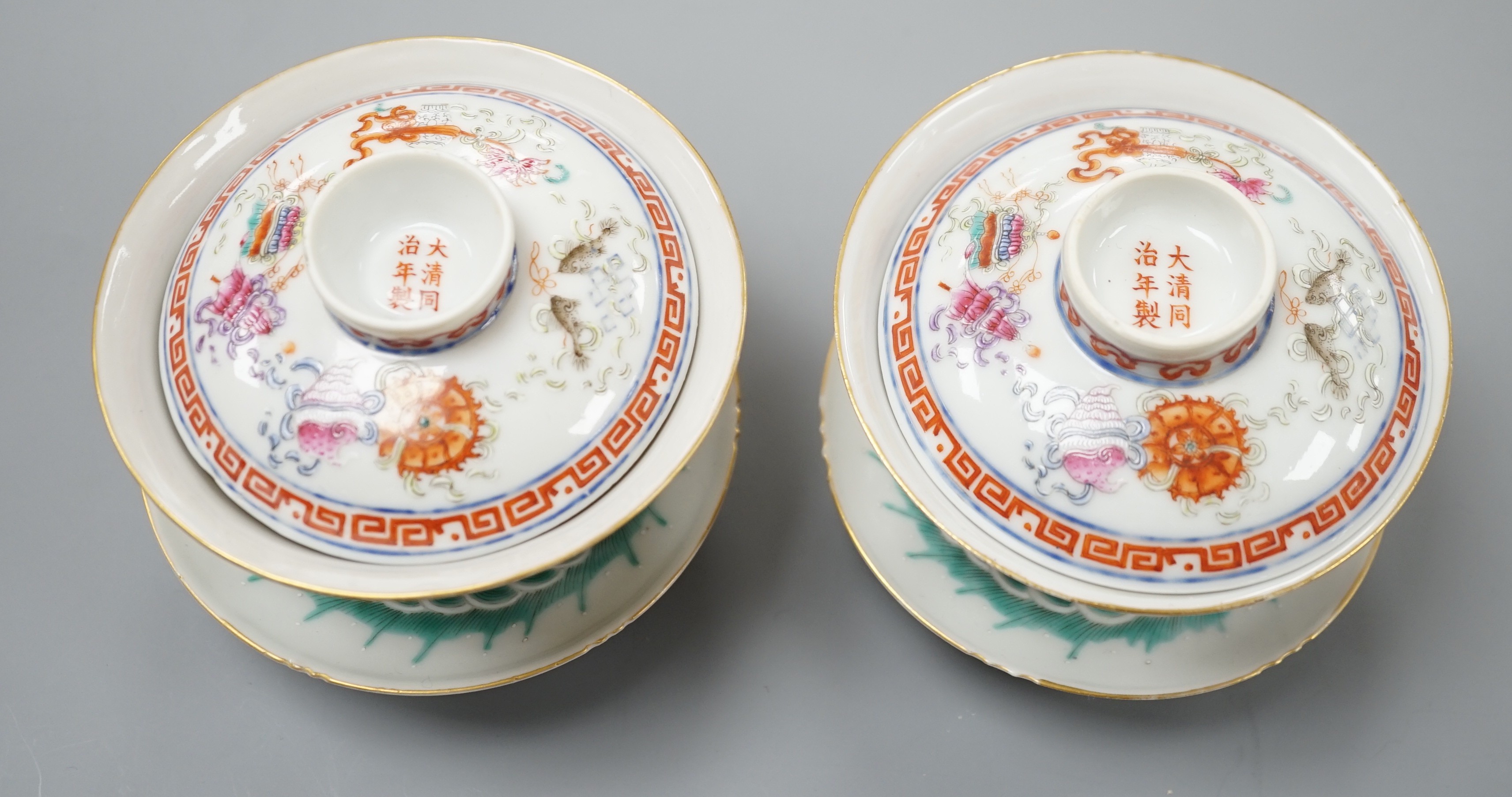 A pair of Chinese famille rose bowls, covers and stands painted with the 8 Buddhist emblems, 9cm total height